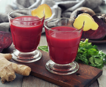 Beetroot smoothie in glass with ginger and  fresh vegetables on wooden background