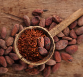 cocoa powder in spoon on roasted cocoa chocolate beans background