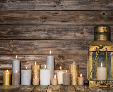 Wooden vintage background in with many burning candles and a old rustic lantern.