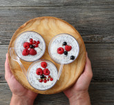 Chia seeds pudding with berries on plate, men's hands holding dish
