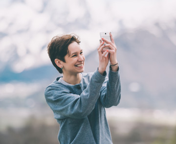 Young woman taking pictures on smartphone  in mountains. Tourism and leisure concept. Focus on hands