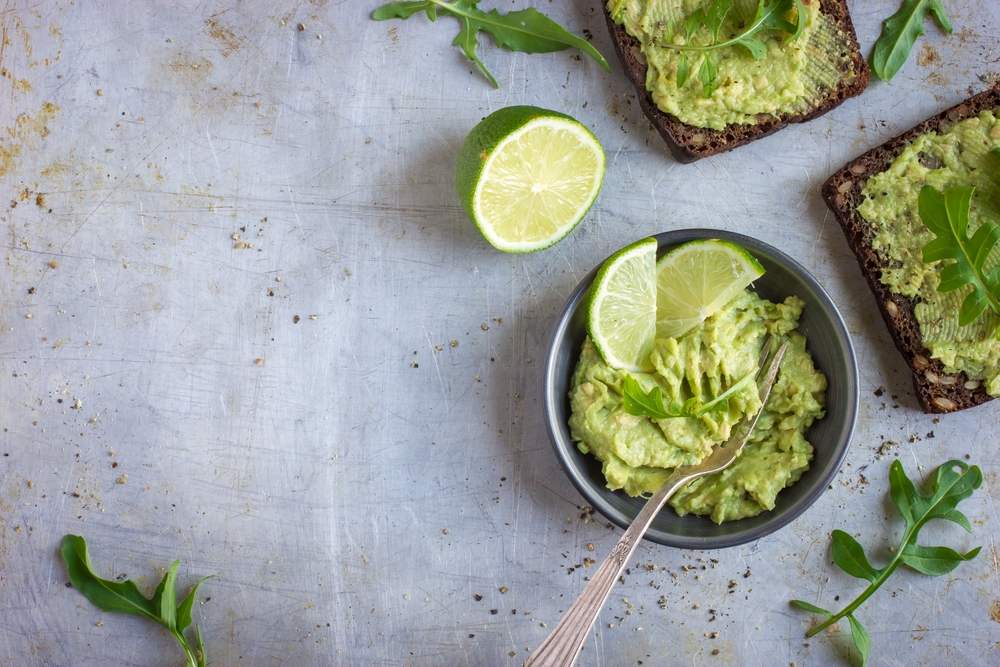 guacamole and rye toasts on rustic background, top view, copy space