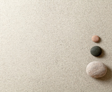 Three colorful zen stones at right side of sand background