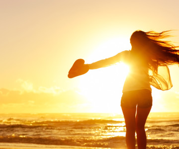 carefree woman dancing in the sunset on the beach. vacation vitality healthy living concept